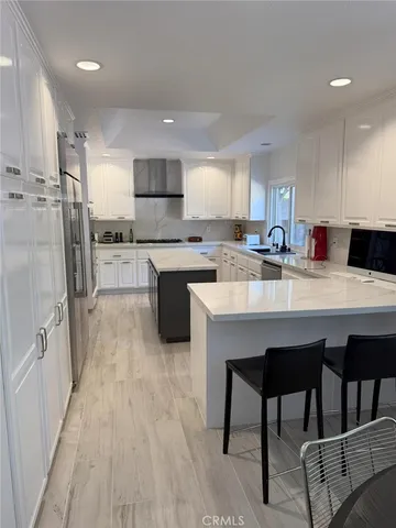 a kitchen with stainless steel appliances granite countertop a table chairs sink refrigerator and cabinets