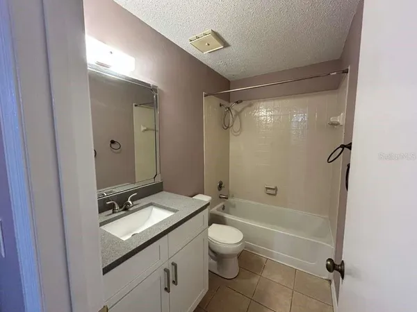 a bathroom with a granite countertop sink toilet a mirror and shower
