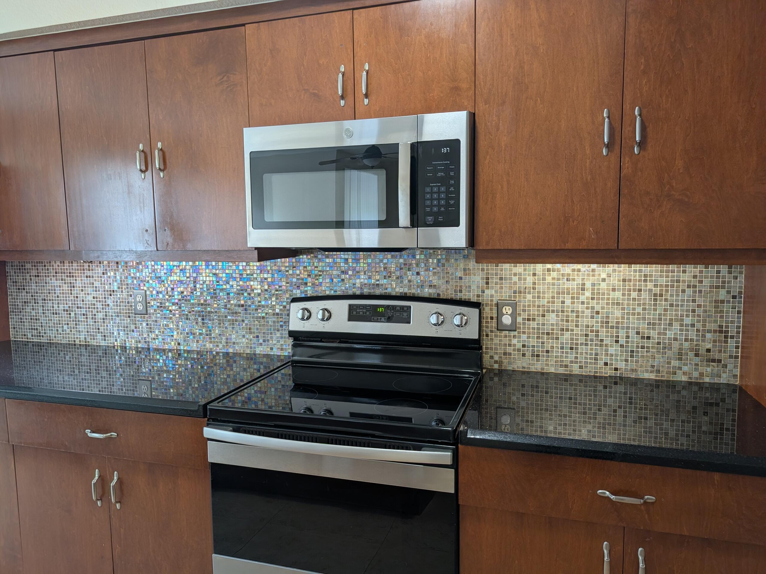 6966 West Sample Road, Unit 6966 Coral Springs, FL 33067 - Photo 4 of 58 a kitchen with granite countertop a stove and a microwave