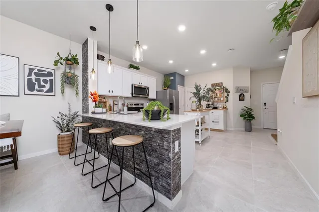 a room with stainless steel appliances kitchen island a table and chairs in it