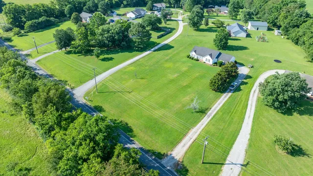 an aerial view of a residential houses with outdoor space and trees all around
