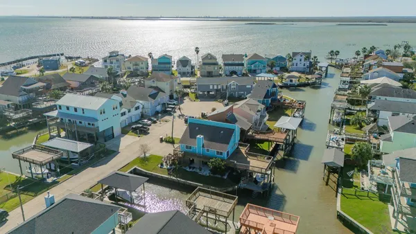 an aerial view of a city with lots of residential buildings ocean and mountain view in back
