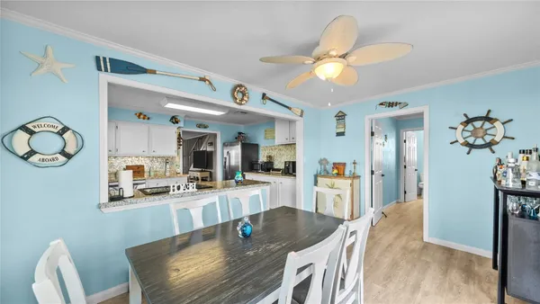 a dining room with wooden floor a chandelier fan a wooden table and chairs