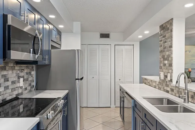 a kitchen that has a sink a stove and a refrigerator