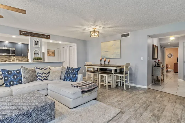 a living room with furniture kitchen view and a wooden floor