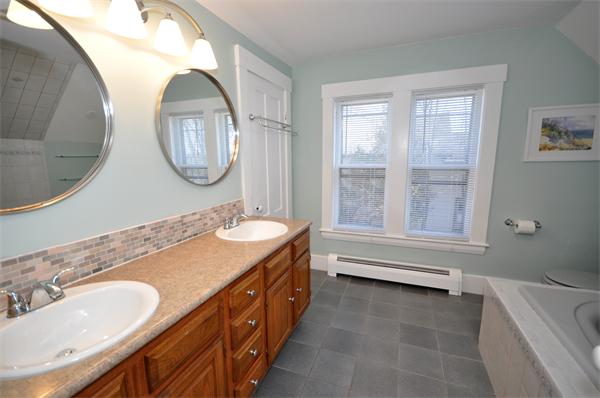62 Central Street Framingham, MA 01701 - Photo 18 of 23 a bathroom with a double vanity sink a mirror a bathtub and a window