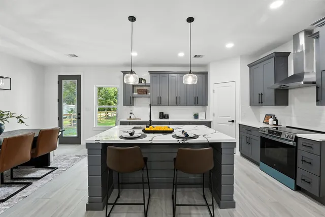 a kitchen with stainless steel appliances granite countertop a stove a sink dishwasher a dining table and chairs with wooden floor