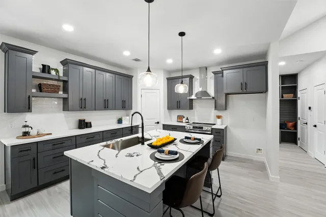 a kitchen with a sink a stove a refrigerator and a dining table with wooden floor