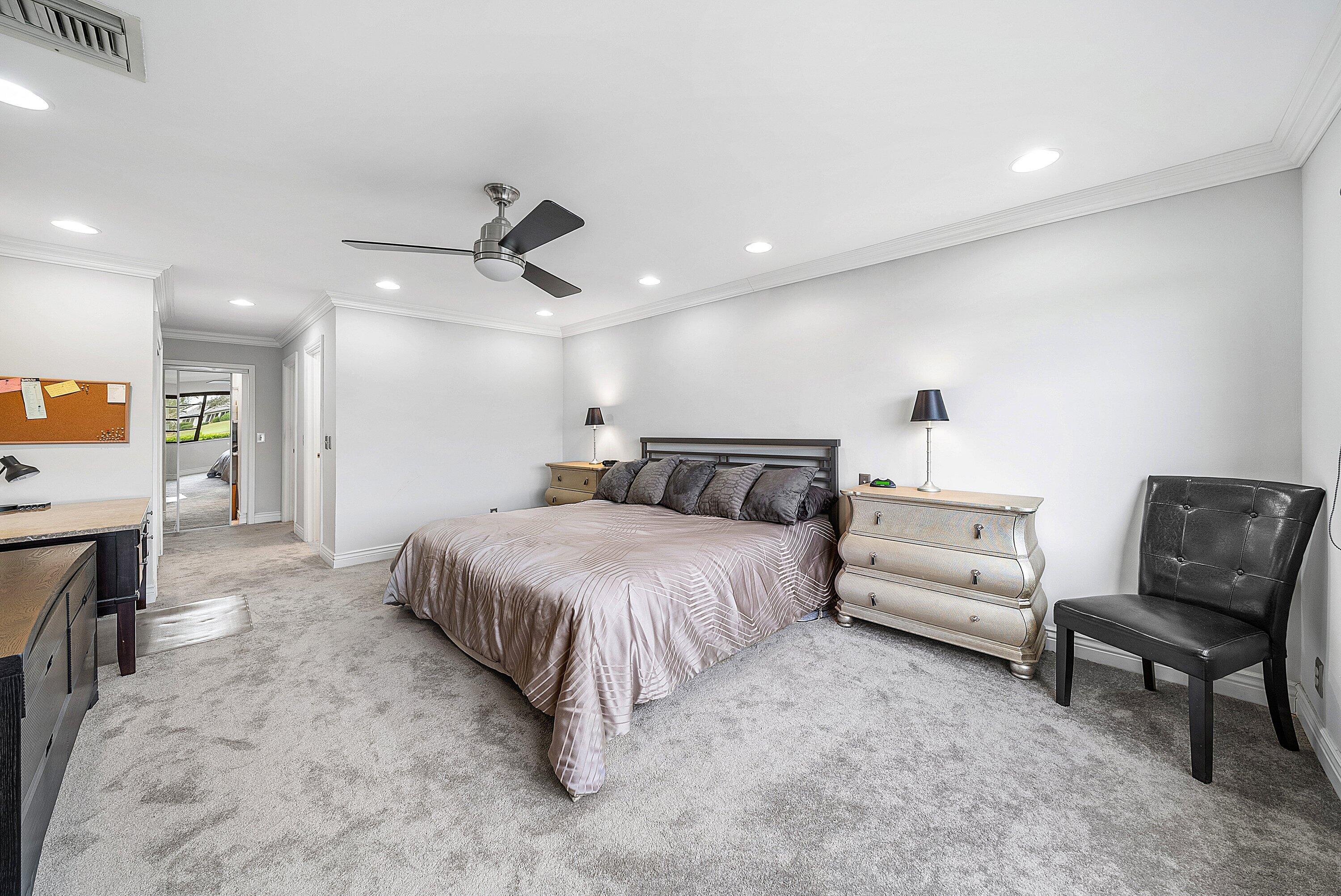 23 Eastgate Drive, Unit C Boynton Beach, FL 33436 - Photo 26 of 71 a spacious bedroom with a bed a couch and a chandelier