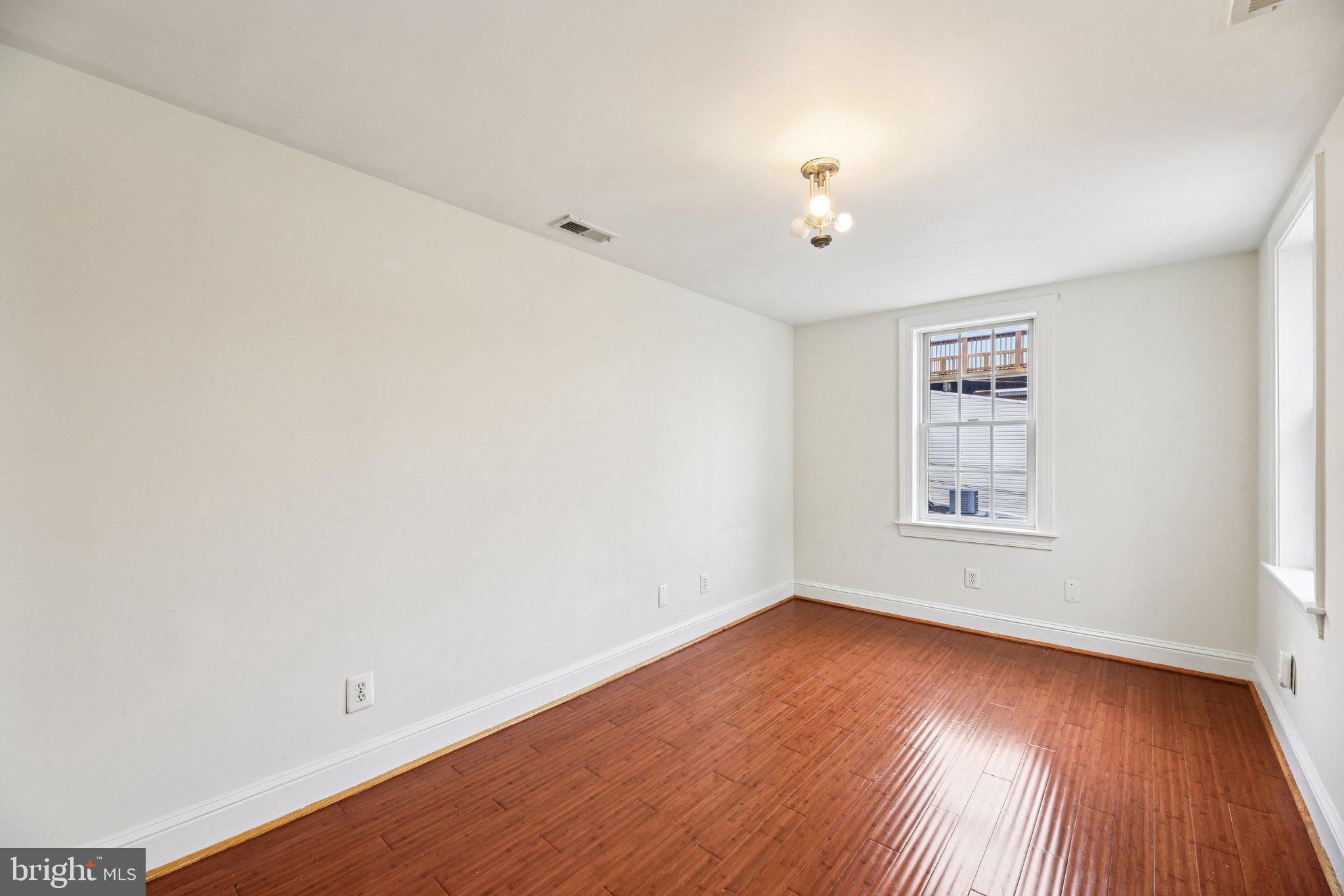 2341 Eastern Avenue Baltimore, MD 21224 - Photo 17 of 43 an empty room with wooden floor chandelier fan and windows