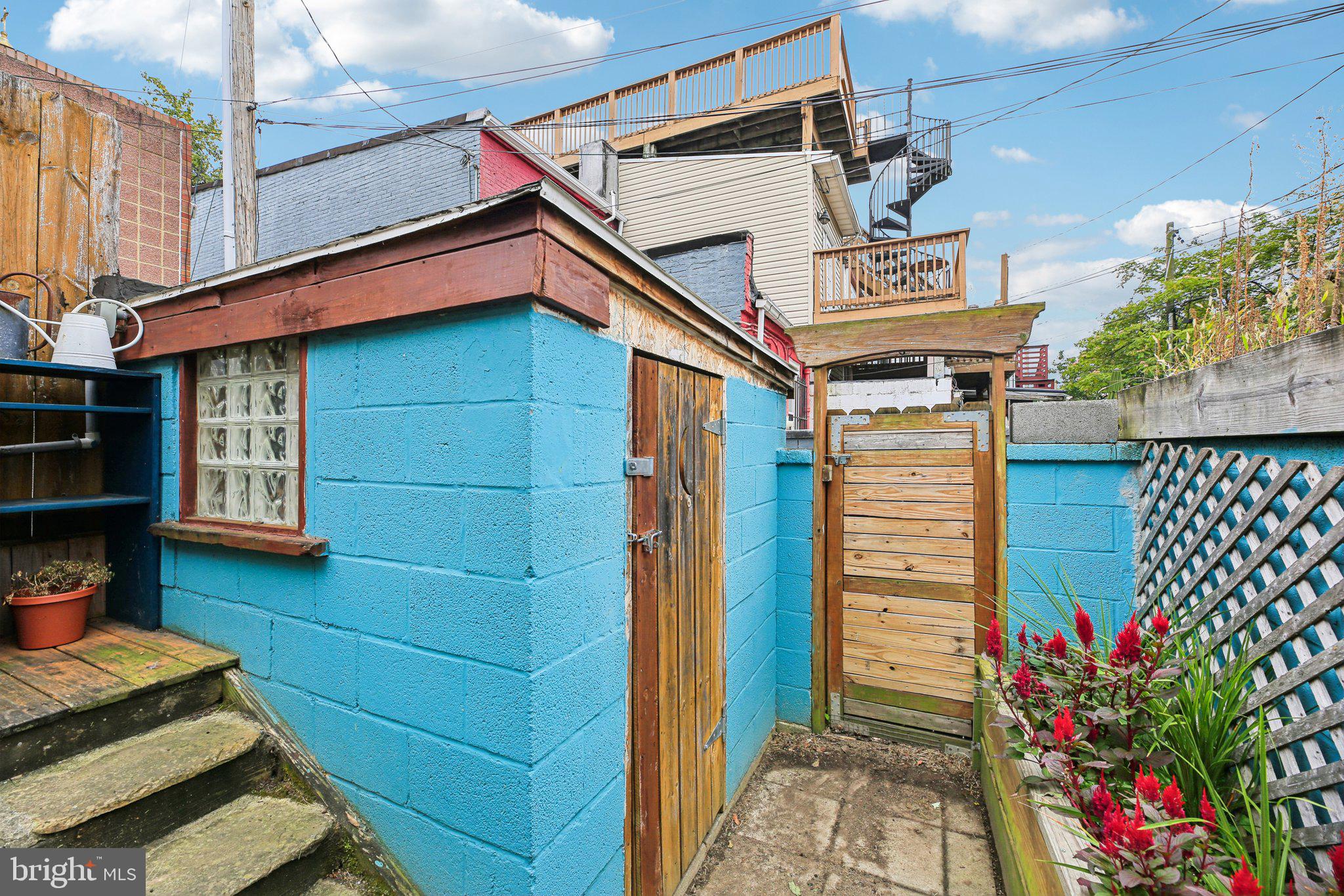 2341 Eastern Avenue Baltimore, MD 21224 - Photo 25 of 43 a yellow house with flower garden and wooden fence