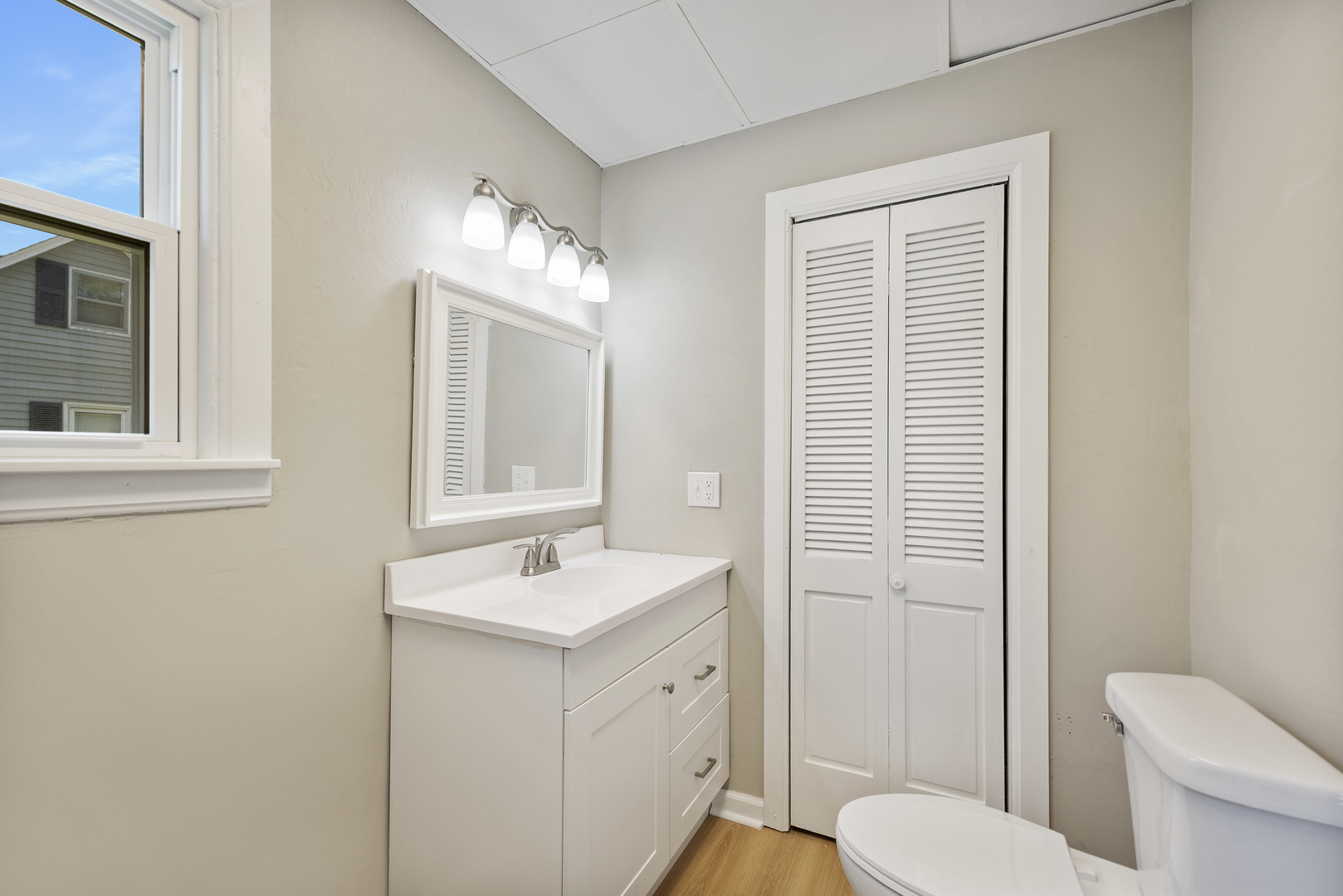 722 East Madison Avenue Chrisman, IL 61924 - Photo 17 of 23 a bathroom with a toilet a sink a mirror a window and vanity