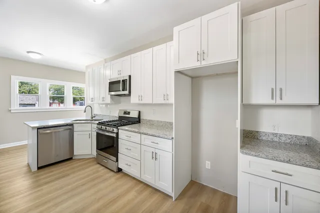 a kitchen with granite countertop white cabinets and stainless steel appliances