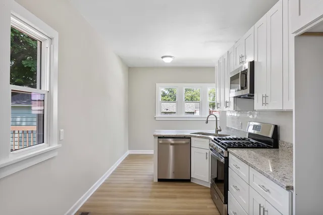 a kitchen with stainless steel appliances a sink cabinets and a window