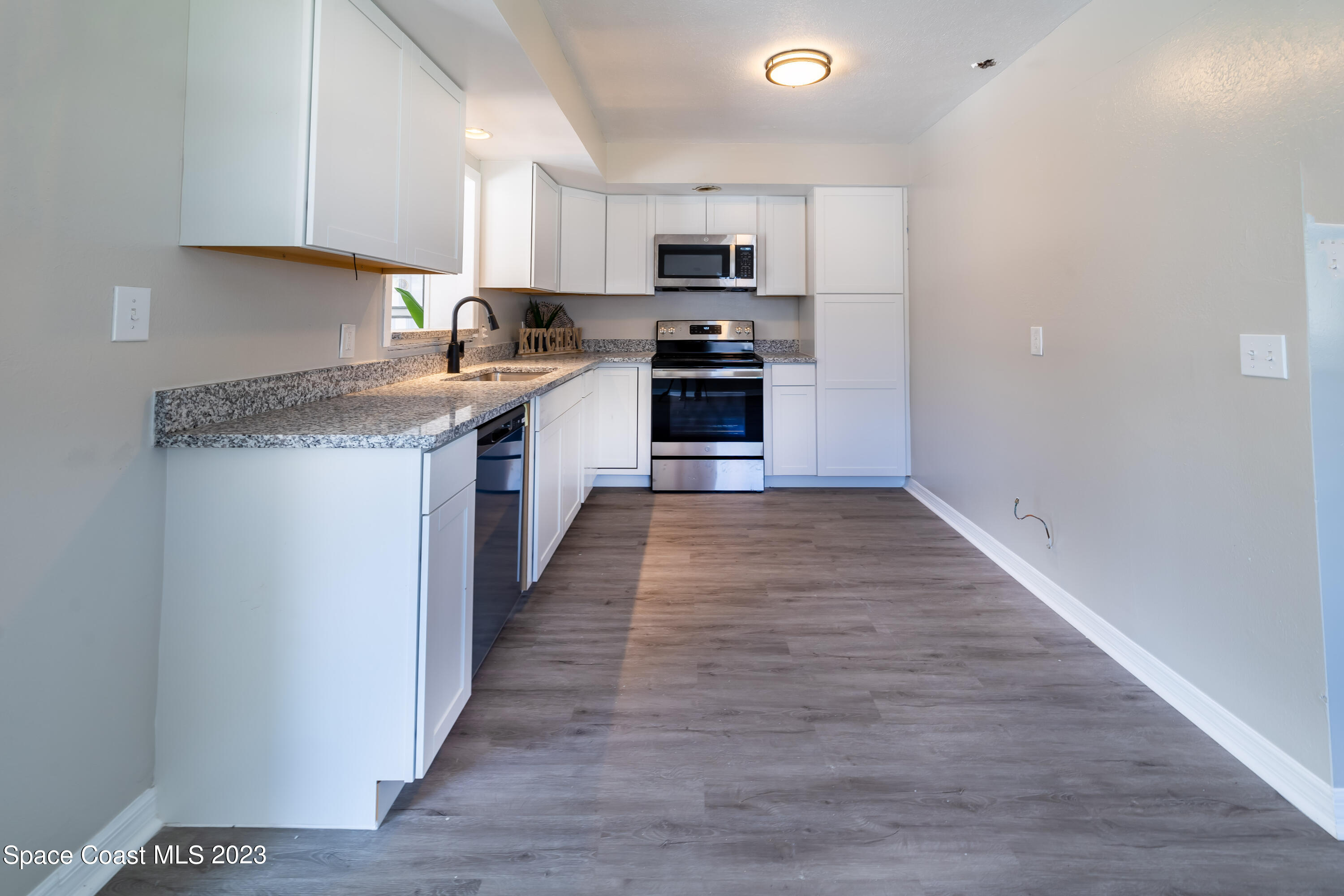 2411 Dairy Road Melbourne, FL 32901 - Photo 10 of 25 a large kitchen with cabinets wooden floor and stainless steel appliances