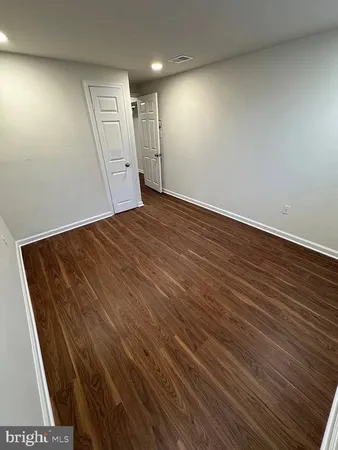 an empty room with wooden floor and natural light