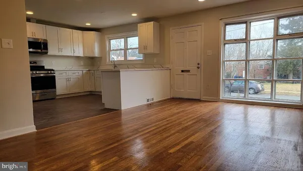 a kitchen with granite countertop wooden floors stainless steel appliances and sink