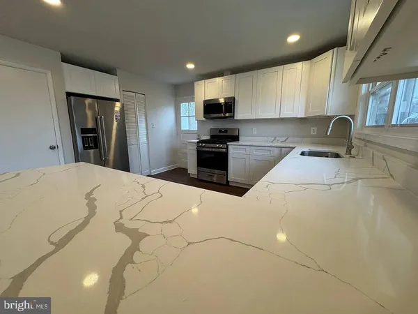 a large kitchen with stainless steel appliances kitchen island a stove a sink a refrigerator and cabinets