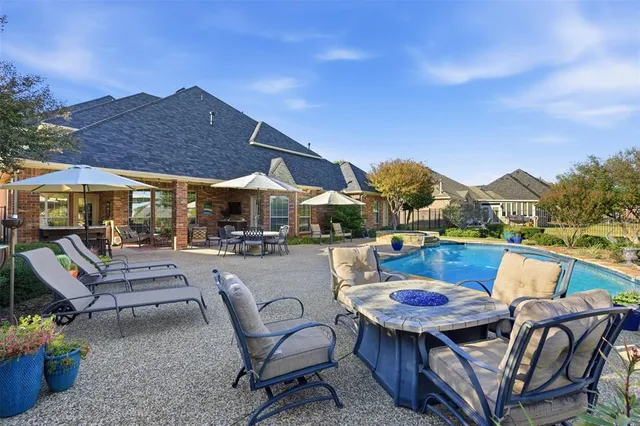a view of a patio with couches table and chairs under an umbrella with a fire pit