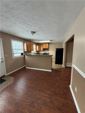 a view of a livingroom with wooden floor and a kitchen