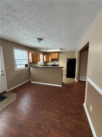 a view of a livingroom with wooden floor and a kitchen