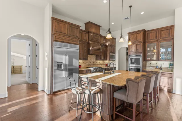 a kitchen with stainless steel appliances granite countertop a stove a refrigerator a oven a sink with a dining table and chairs