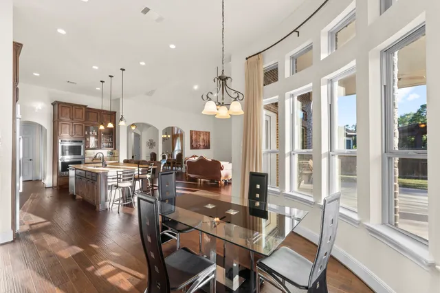 a view of a dining room and livingroom with furniture wooden floor kitchen chandelier