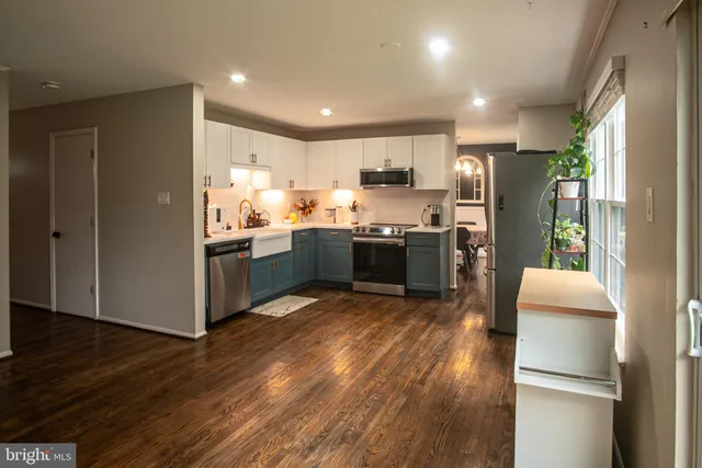 a kitchen with stainless steel appliances granite countertop a refrigerator a sink dishwasher a stove and a microwave oven with wooden floor