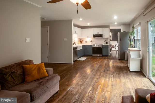 a living room with stainless steel appliances furniture large window and wooden floor