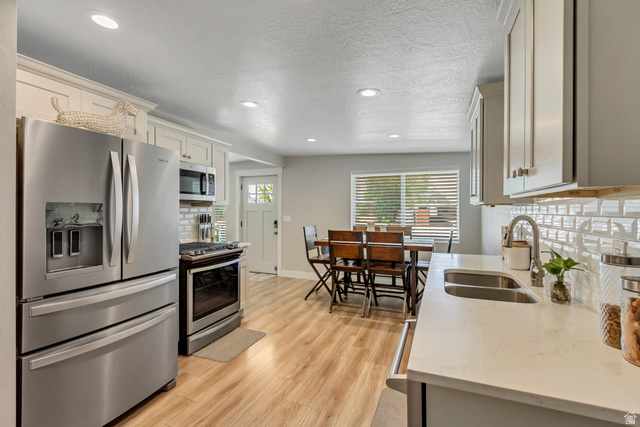 48 Moon Ridge Drive Murray, UT 84107 - Photo 8 of 30 Contemporary kitchen with light wood-finish flooring, white cabinetry, and stainless steel appliances