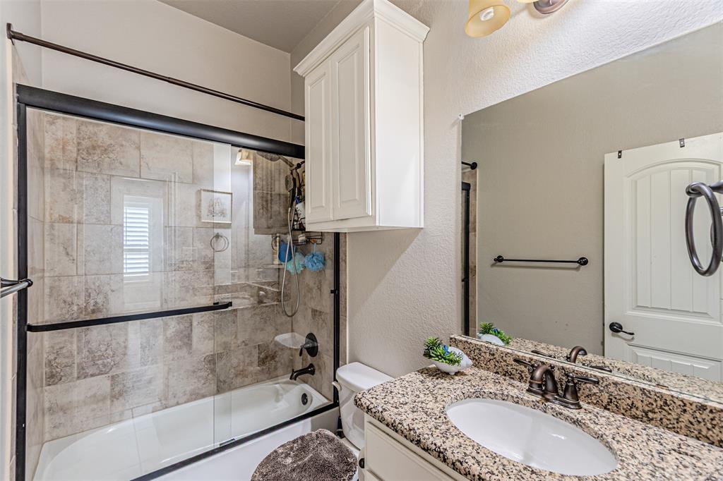 1805 Stetson Way Allen, TX 75002 - Photo 19 of 22 Bathroom featuring a shower-tub combination with tile surround and glass enclosure, a single vanity with stone countertop and undermount sink, and white cabinetry