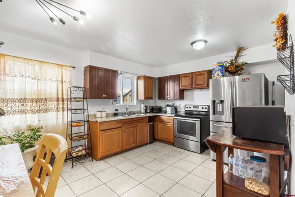 a kitchen with stainless steel appliances granite countertop a stove top oven a sink dishwasher a dining table and chairs with wooden floor