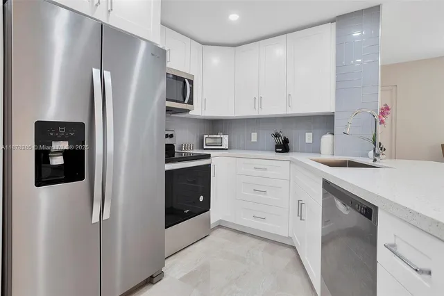a kitchen with white cabinets and sink