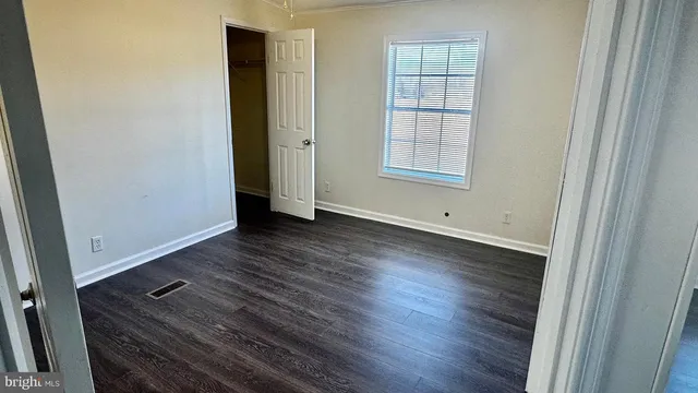an empty room with wooden floor and window