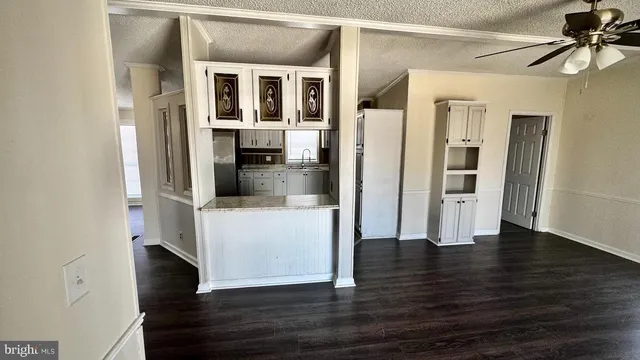 a view of a hallway with wooden floor and a living room