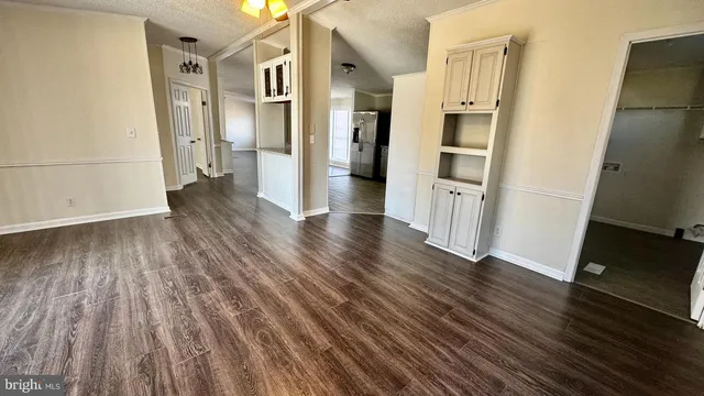 an empty room with wooden floor and a kitchen