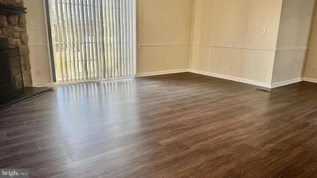 an empty room with wooden floor and windows with curtains