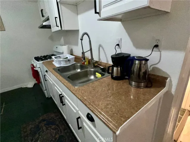 a kitchen with sink a stove and cabinets