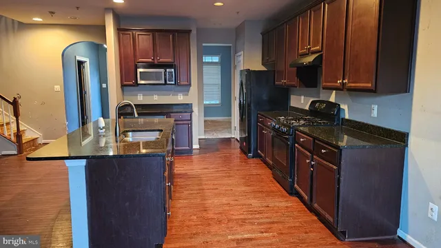 a kitchen with granite countertop a sink cabinets and wooden floor