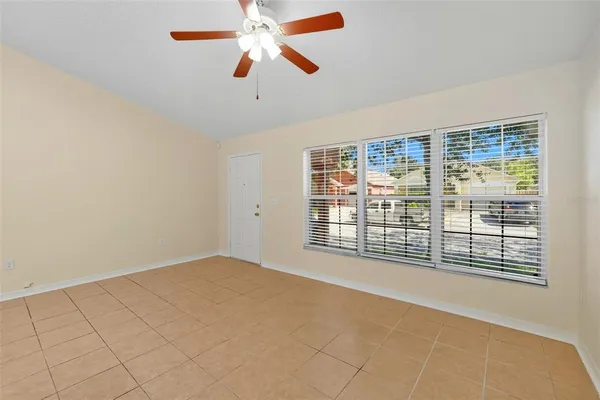an empty room with chandelier fan and windows