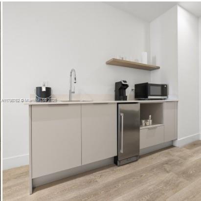 229 Southwest 9th Street, Unit 404 Miami, FL 33130 - Photo 9 of 11 a kitchen with cabinets and wooden floor