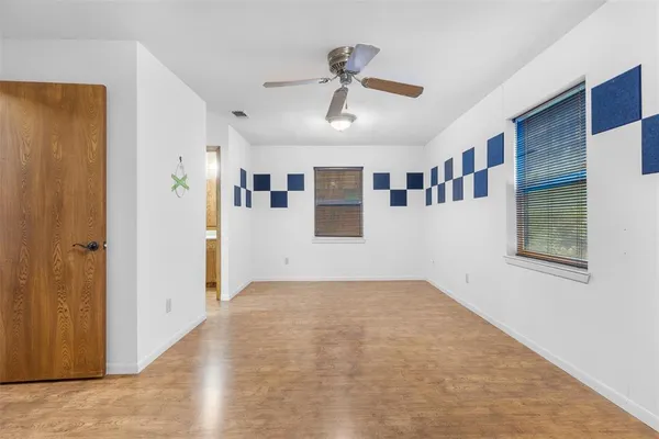 a view of empty room with wooden floor and ceiling fan