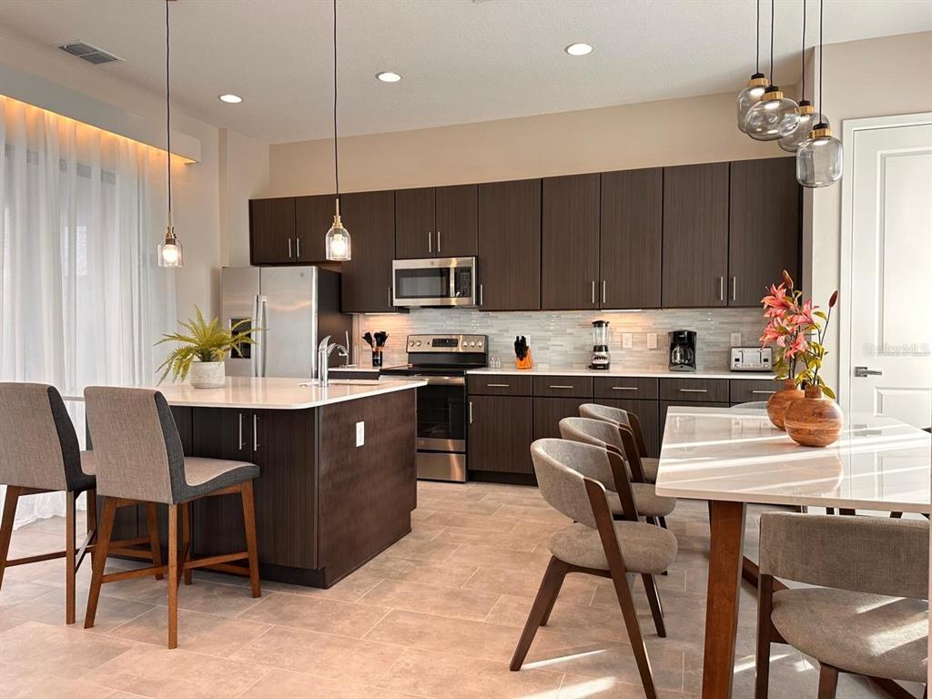 304 Villa Domani Court Davenport, FL 33896 - Photo 2 of 37 a kitchen with kitchen island a dining table chairs and a sink
