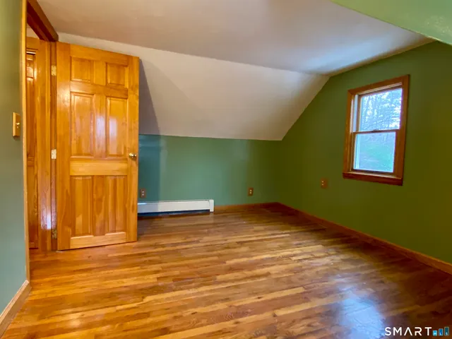 a view of empty room with window and wooden floor