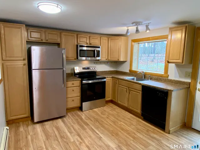 a kitchen with stainless steel appliances granite countertop a refrigerator a sink dishwasher a stove top oven a refrigerator with island and chairs