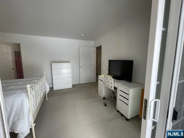 a bedroom with a bed and a flat tv screen on the dresser