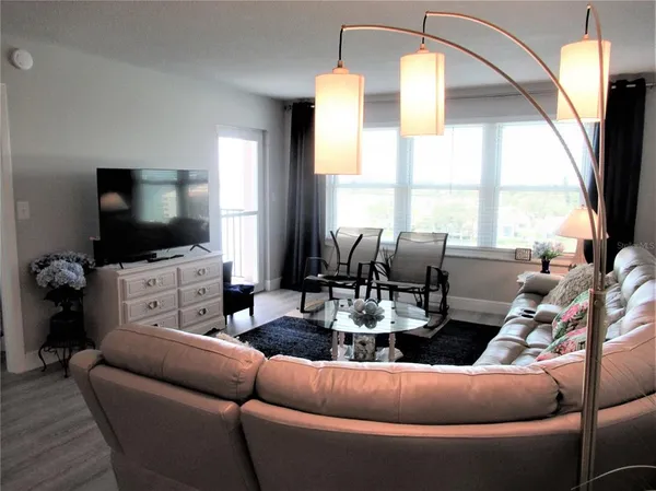 a living room with furniture a flat screen tv and a large window
