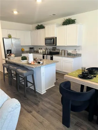 a kitchen with stainless steel appliances granite countertop a table chairs sink and cabinets