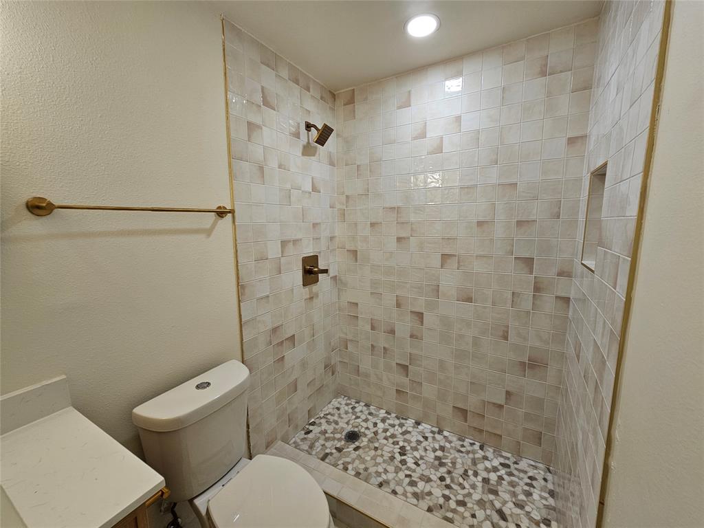 1725 R Avenue, Unit 1725 Plano, TX 75074 - Photo 10 of 20 Walk-in shower featuring mosaic pebble flooring, tiled walls with an integrated niche, and bronze-finish fixtures