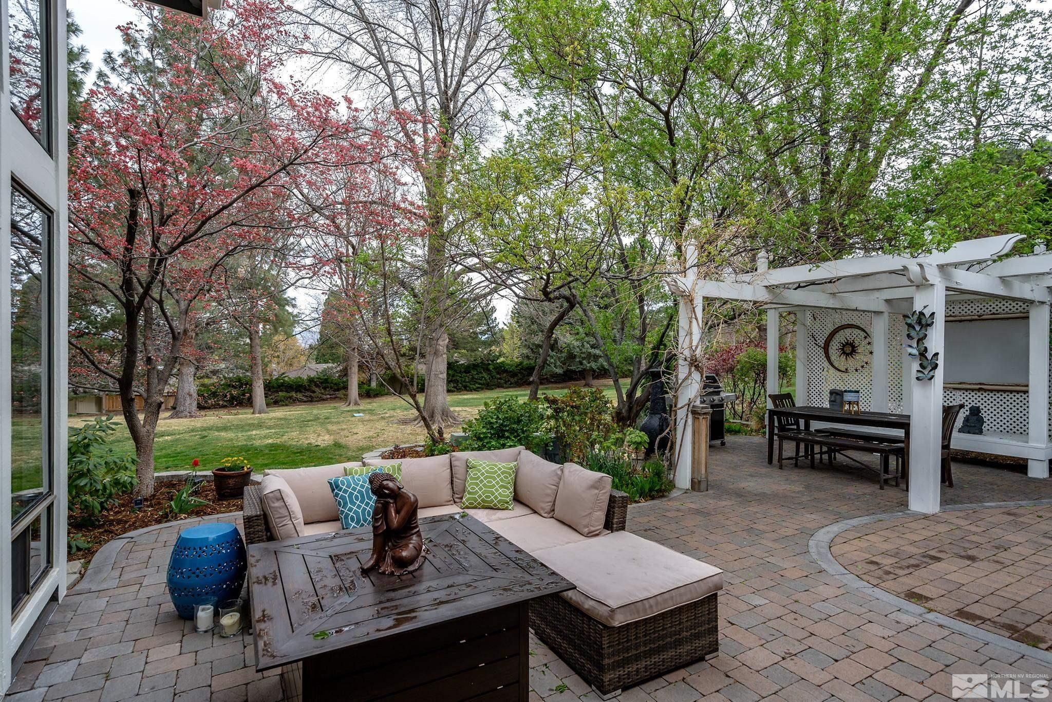 2720 West Lakeridge Reno, NV 89519 - Photo 33 of 40 a view of a patio with couches table and chairs under an umbrella with large trees